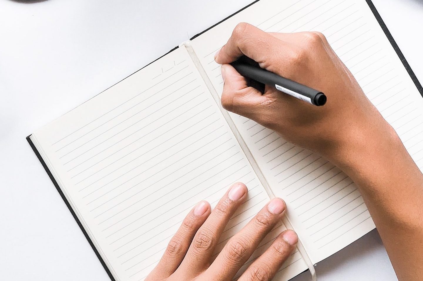 person writing on white notebook